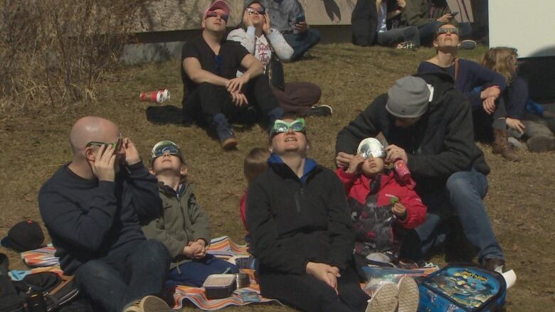 People sit on the grass wearing glasses. 