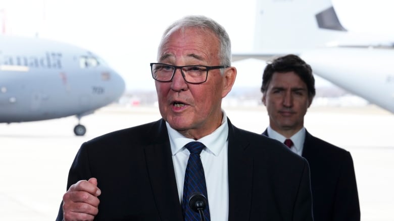 Prime Minister Justin Trudeau stands behind National Defence Minister Bill Blair as they hold a press conference on Canada's new defence policy at CFB Trenton in Trenton, Ont. on Monday, April 8, 2024.