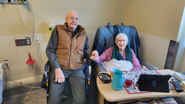 An elderly couple sitting beside each other.