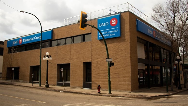 A brown brick building has blue signs at the top and a traffic light in the foreground.