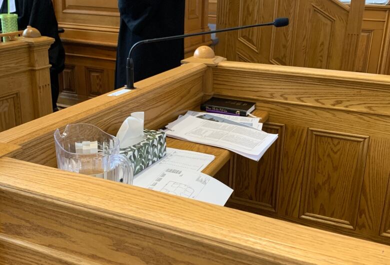 A wooden dock. A box of tissues and papers are in the dock.