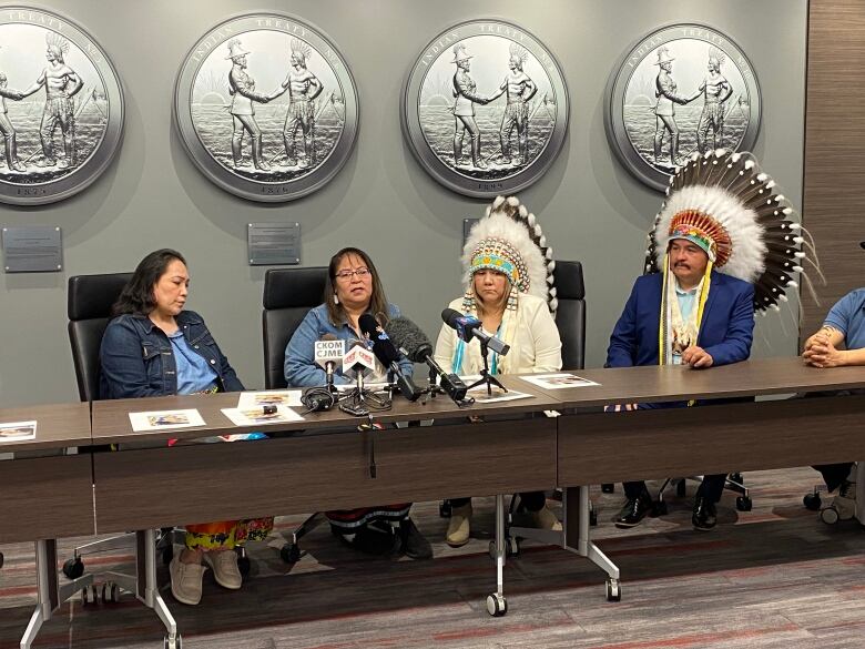 A group of men and men, sit at a table to talk to the media. 