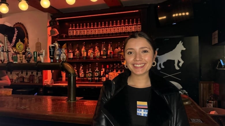 A girl smiling inside a dimly-lit bar. 