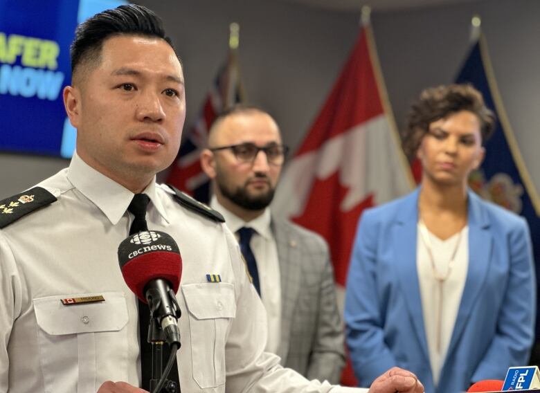 London Police Chief Thai Truong speaks about the hiring of Treena MacSween as the third deputy chief at a podium while she and police services board chair Ali Chahbar look on. 