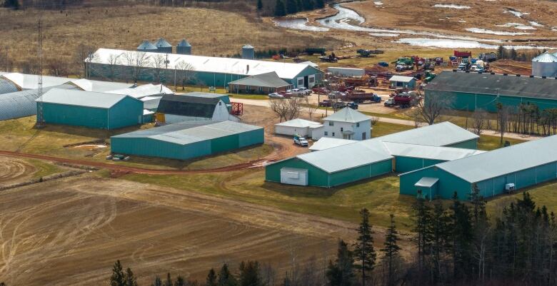 Farm buildings and machinery beside a potato field in spring.