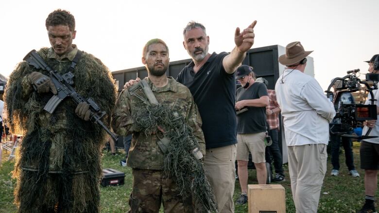 Alex Garland is seen on set of the movie Civil War along with two men in army fatigues.