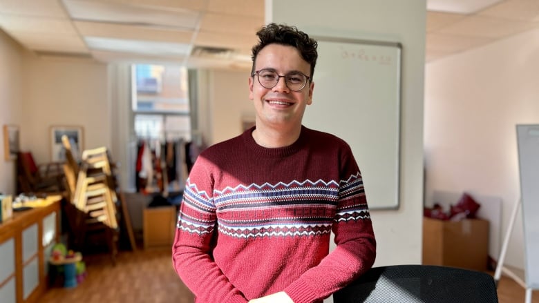 A man stands smiling in a sunny room. 