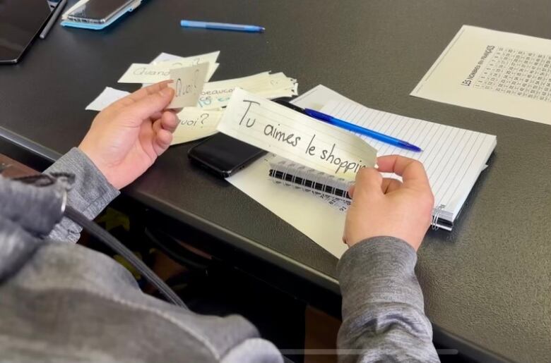 A person holding a small piece of paper in their hand that reads, 