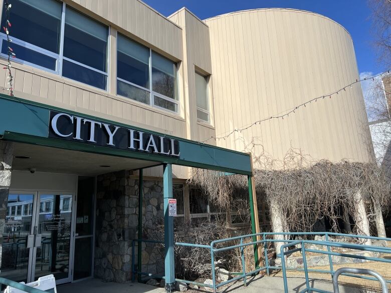 The outside of a building with a 'City Hall' sign above the doors.