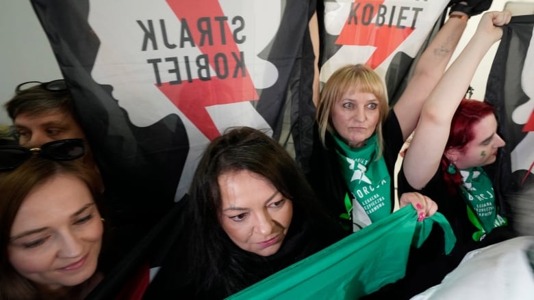 People hold banners and signs  with Polish lettering on them