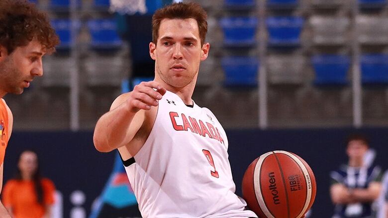 A Canadian men's wheelchair basketball player fends off an opponent while holding the ball in his left hand during play at a Paralympics qualifying tournament on April 13, 2024 in Antibes, France.