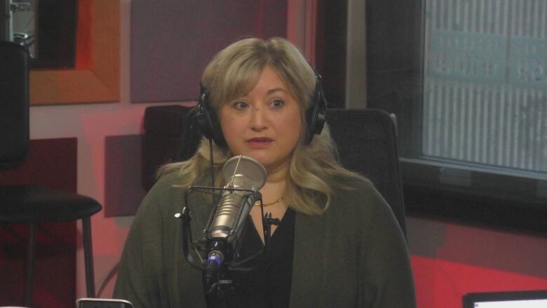 Woman with blond hair and green jacket and black shirt