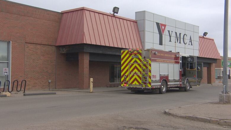 the outside of a YMCA building with YMCA in massive lettering and a fire truck is parked in front