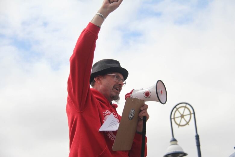 Peter Jongeneelen speaks into a megaphone with one arm raised.