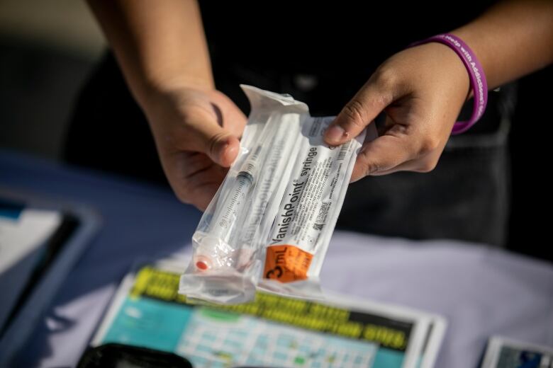 An outreach worker holds a Naloxone kit outside.