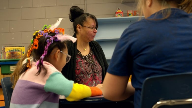 A woman directs children through a game of bingo.