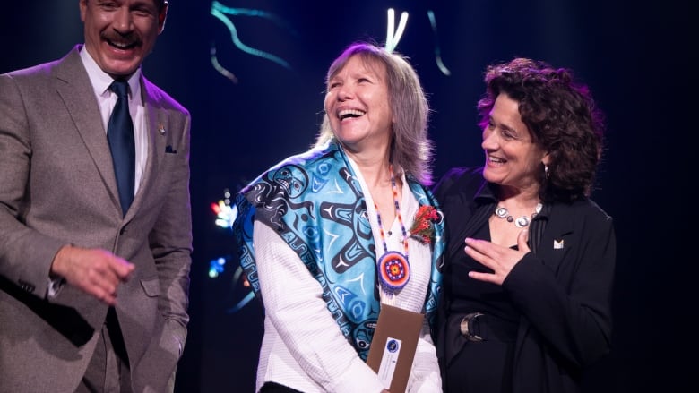 3 people laughing on stage.