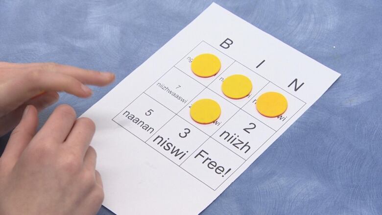 A student covers four spaces on their bingo card as the class in Ashern learns numbers in Anishinabemowin. 