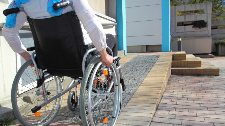 A person wheels up a wheelchair ramp.