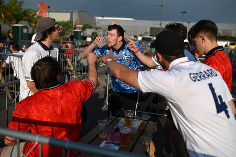 England supporters cheer on a fan to down a pint of beer at the 4TheFans Fan Park in Manchester, as they wait to watch the UEFA EURO 2020 football match between England and Czech Republic, being played in London on June 22, 2021. (Photo by Oli SCARFF / AFP) (Photo by OLI SCARFF/AFP via Getty Images)