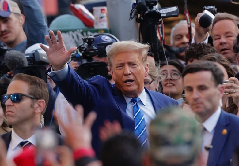 A man in a crowd waves.