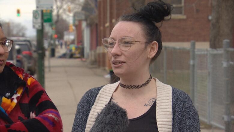 A photo of Alexa Roland in a grey shirt with a choker around her neck and thin eye glasses. 