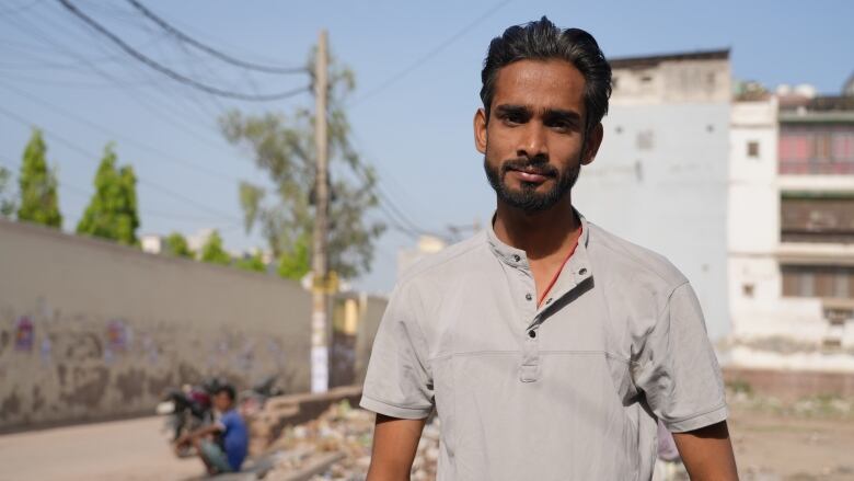 A man stands with a building in the background.