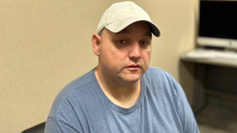 A man wearing a blue shirt and baseball cap.