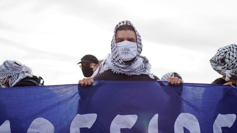 Protesters who blocked a rail line in Toronto on Tuesday wear keffiyehs. The protest was organized by World Beyond War on April 16, 2024.