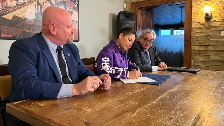 People sitting at a table signing a document. 