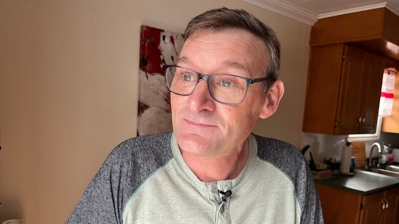 A portrait style photo of a man in his early 50s, inside his house in Shoe Cove.