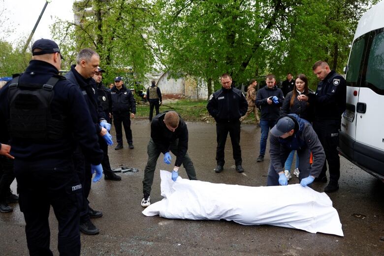 Police officers stand next to a body of a killed person at the site of a Russian missile strike, amid Russia's attacks on Ukraine, in Chernihiv, Ukraine April 17, 2024. 