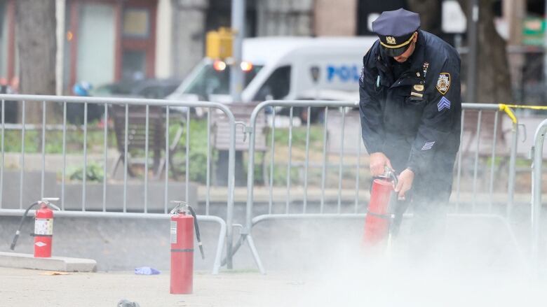 A police officer uses a fire extinguisher outside the New York court house where former U.S. president Donald Trump's hush-money trial is being held.