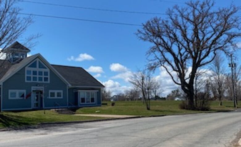 A rural road next to a public library under a blue sky.