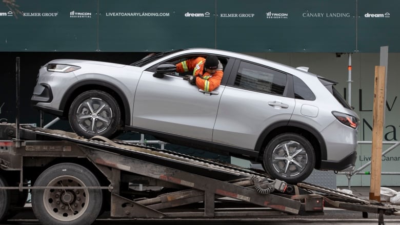 A truck driver is shown in the driver's seat of a vehicle parked on a ramp.