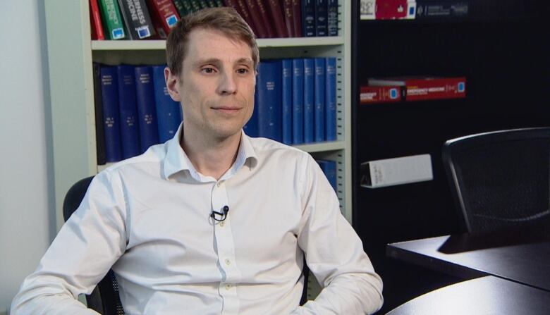 A man in a white shirt sits in an office.