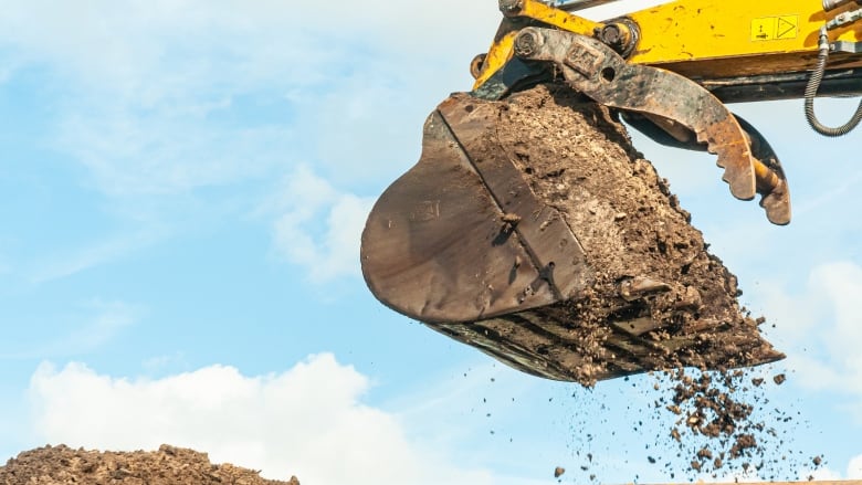 A stock image shows a backhoe digging dirt.