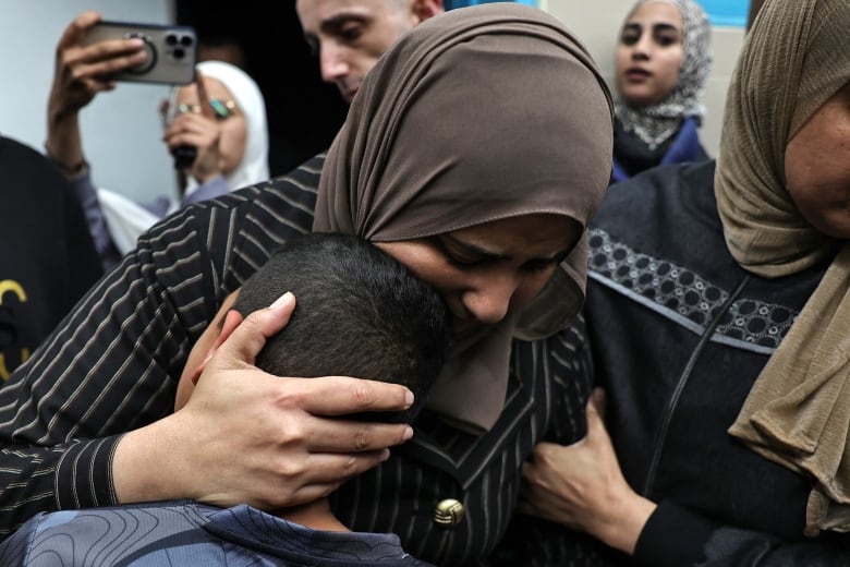 An adult embraces a young child as they mourn.