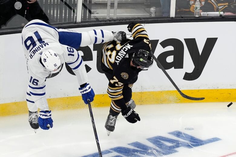 Hockey players from opposing teams are lifted off the ice as they collide.