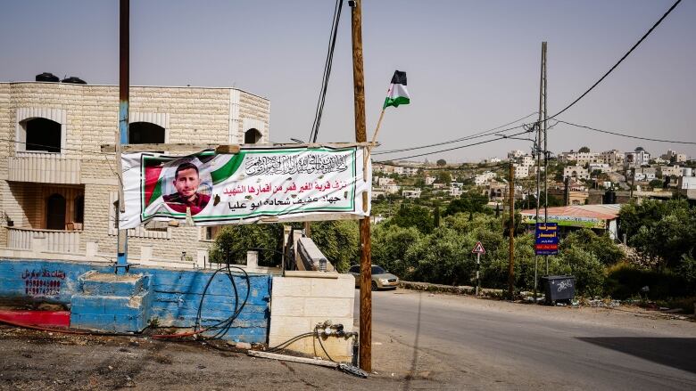 A banner strung between poles shows the picture of a person and some writing.