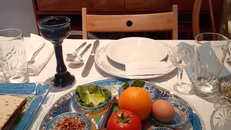 A seder plate atop a white tablecloth featuring various traditional Passover foods.