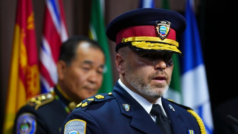 A bearded man in a police chief's uniform speaks.