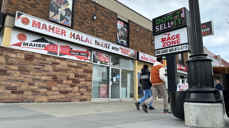 Two men walk past the storefront of Maher Halal meat in Calgary