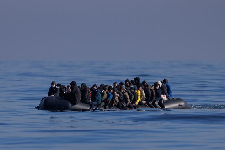 People crowded on a rubber dinghy on the water. 