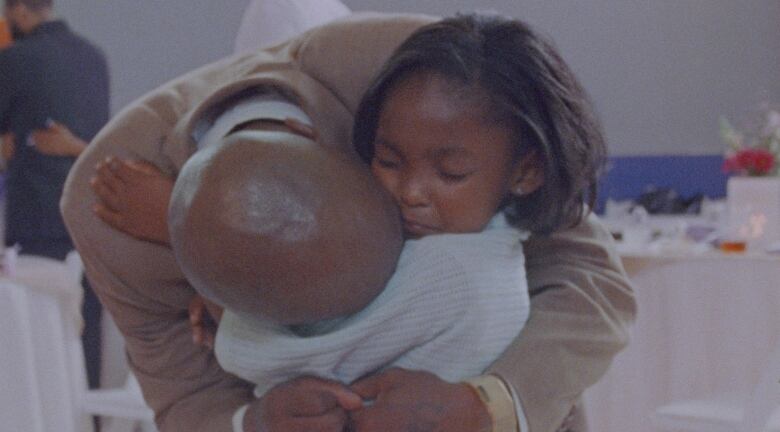 A small girl closes her eyes while hugging a man that holds his head against her shoulder. 