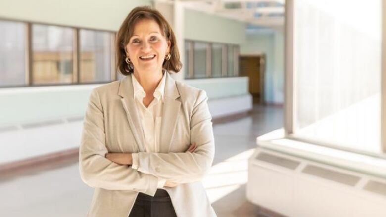 Medium shot of woman smiling at camera with arms crossed