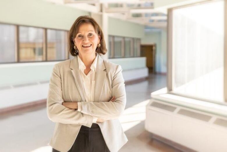 Medium shot of woman smiling at camera with arms crossed