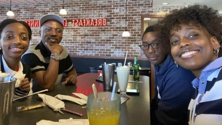 A family of four sits at a restaurant table with drinks in front of them. 