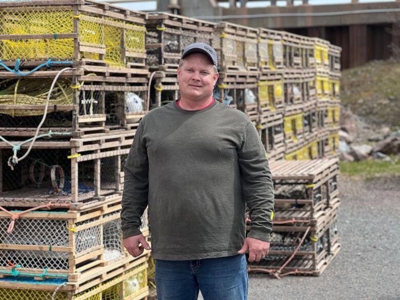 A man stands near some lobster traps 