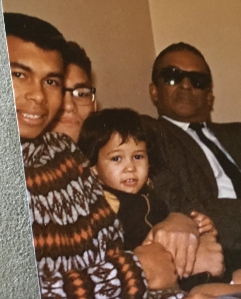 Old photo of three men and young girl sitting on a couch.